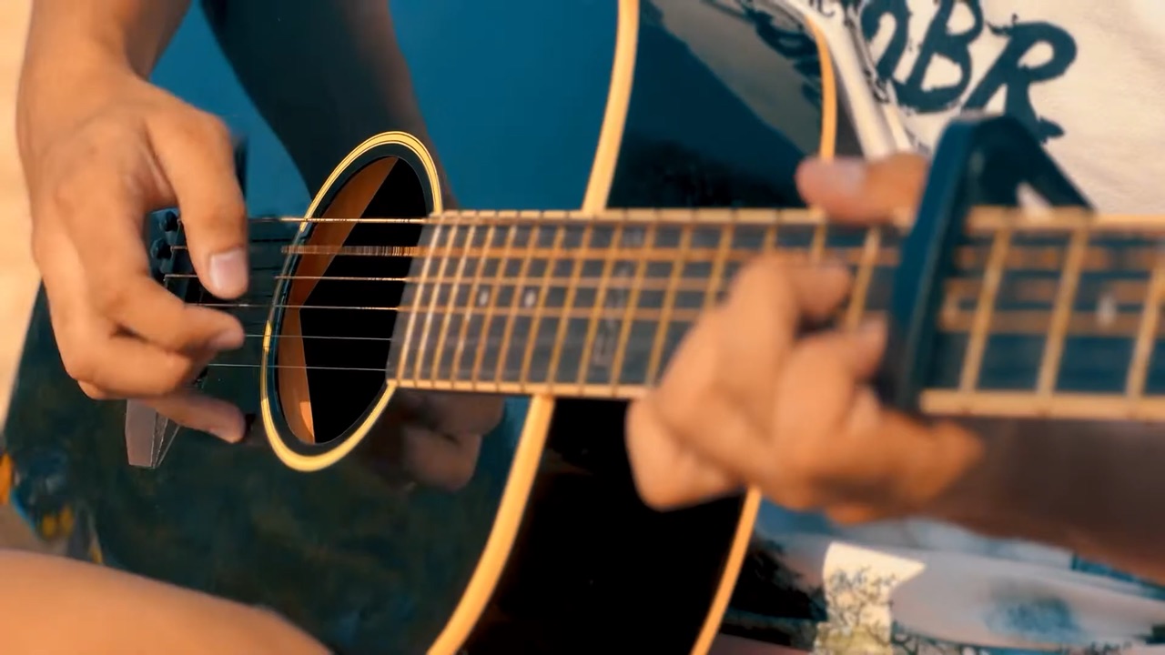 Macro shot of fingers on an acoustic guitar fretboard in warm golden hour light